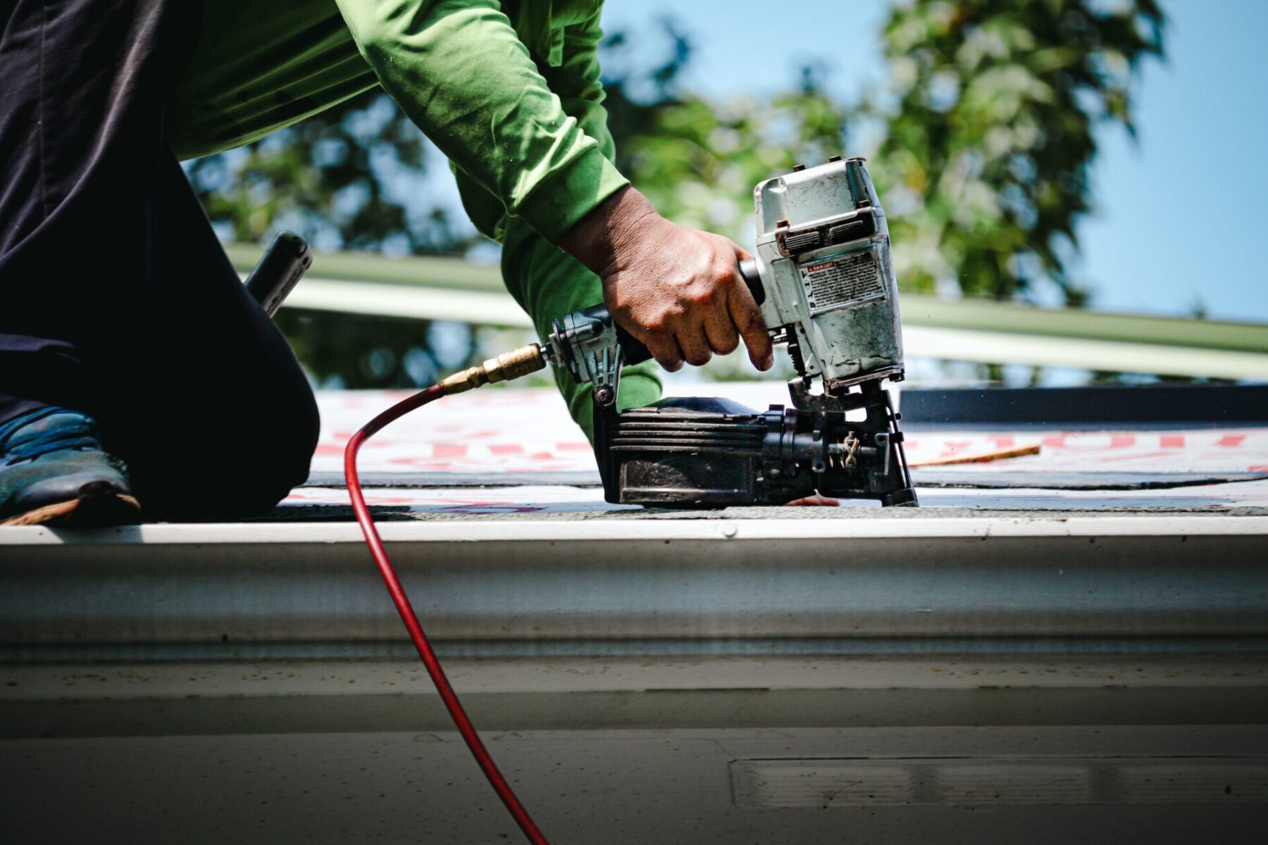 Man using a nail gun on the roof - Stonecreek Roofing